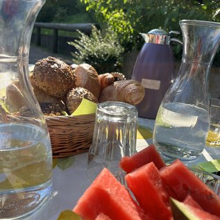 Frühstückstisch im Grünen mit Brötchen und frischer Wassermelone beim Reiturlaub in NRW