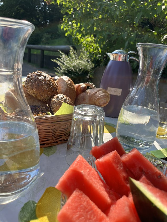 Frühstückstisch im Grünen mit Brötchen und frischer Wassermelone beim Reiturlaub in NRW