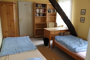 Ein gemütlich eingerichtetes Doppelzimmer mit zwei Holzbetten, einem Schreibtisch und Holzbücherregalen im Reiterhof.